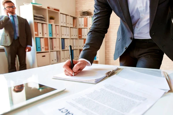 منظور از ورشکستگی شرکت چیست 3 فردی که دارد یک برگه را امضا میکند.